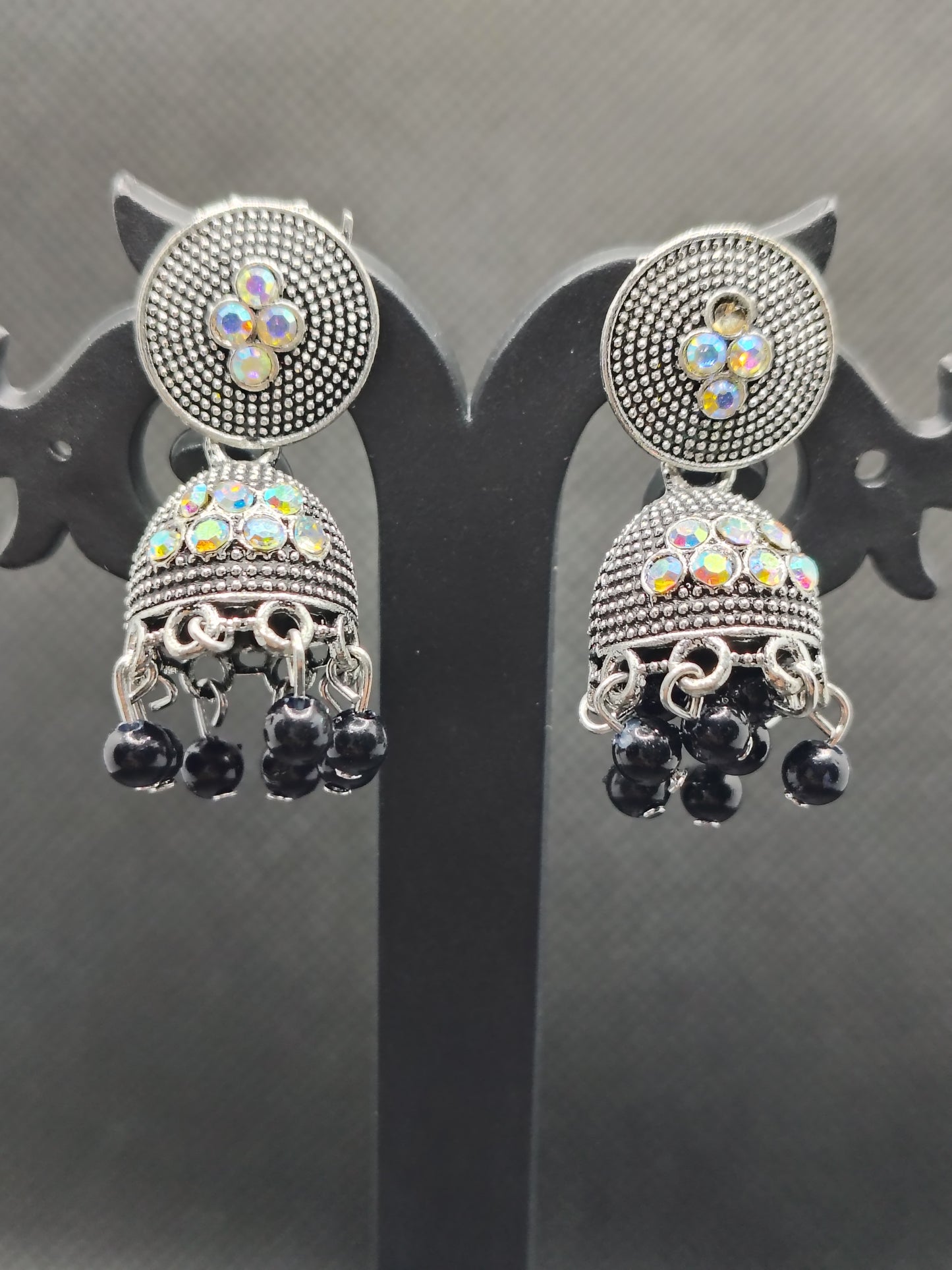 Pair of ornate earrings with gemstones on a reflective surface