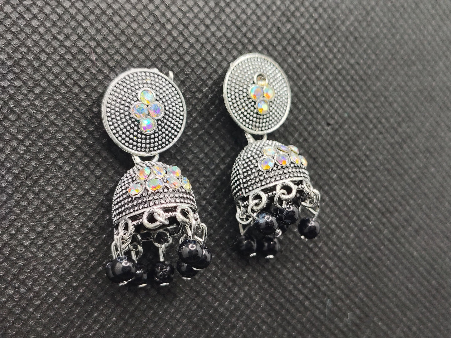 Pair of silver and black earrings on a textured gray surface