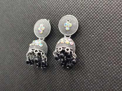 Pair of earrings with black gemstones and colorful stones on a gray textured background