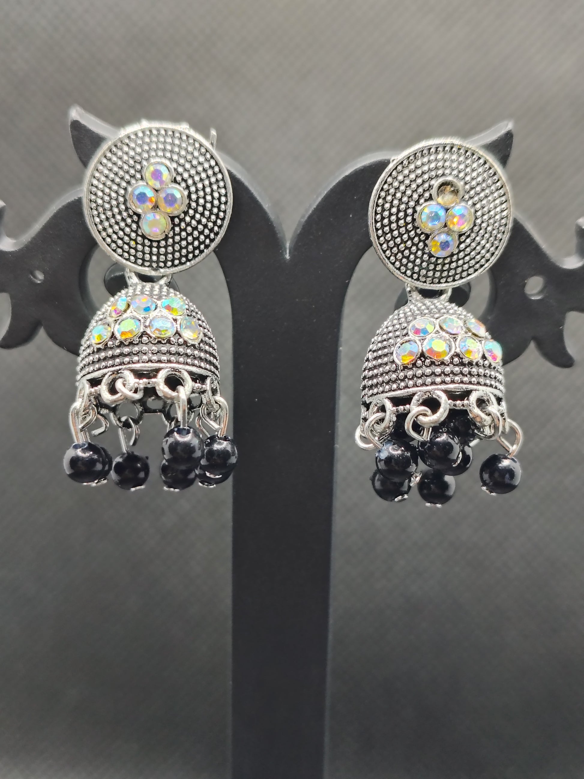 Pair of ornate earrings with gemstones on a reflective surface