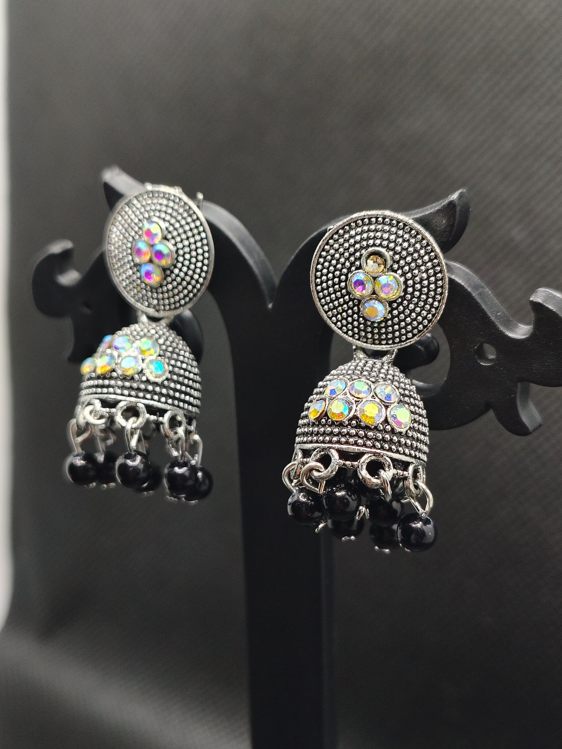 Pair of silver earrings with gemstones on a dark background