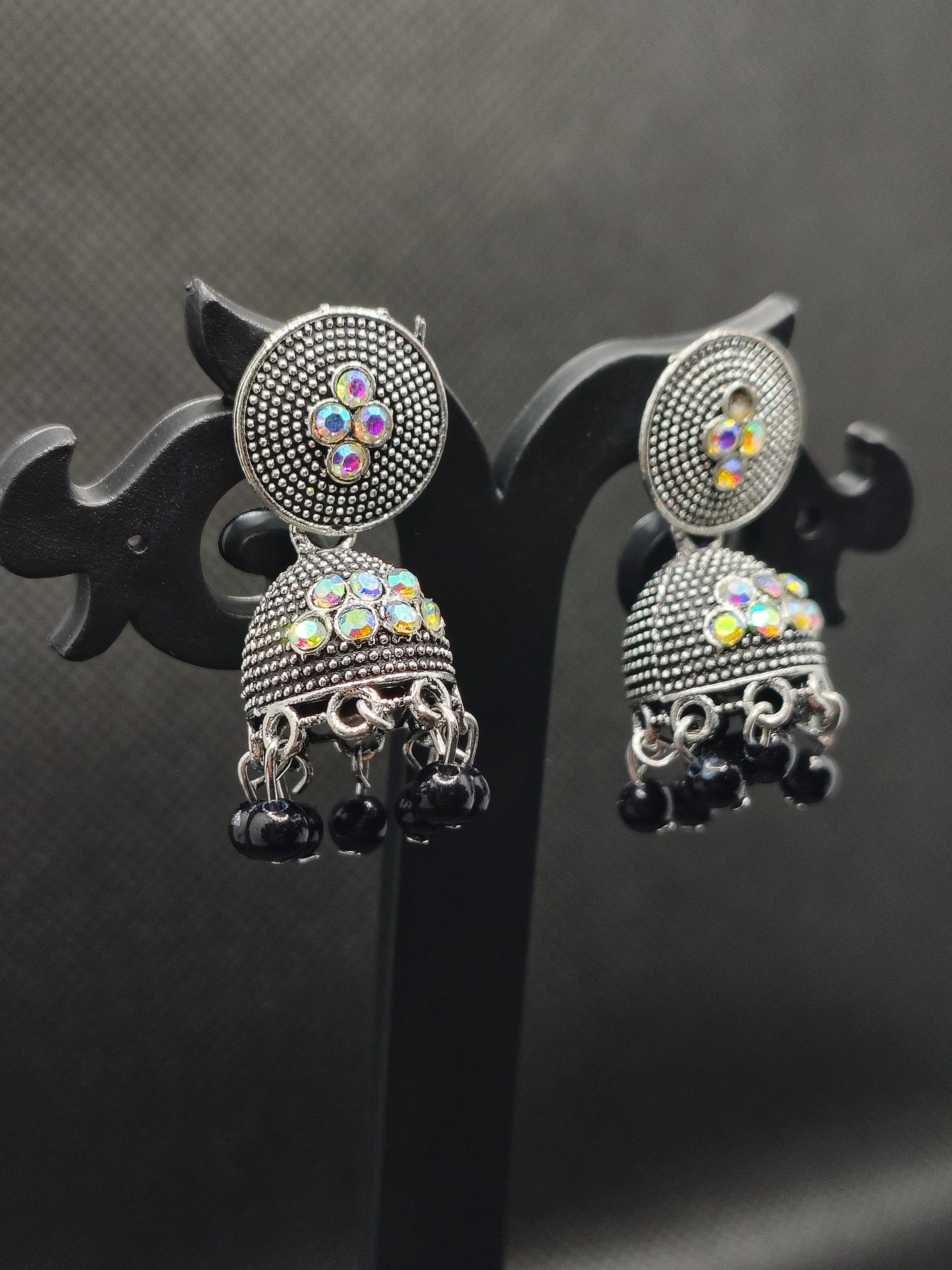 Pair of silver earrings with colorful gemstones on a black background