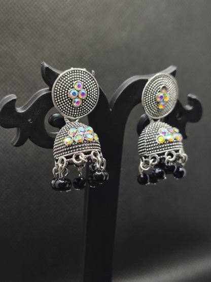 Pair of silver earrings with colorful gemstones on a black background